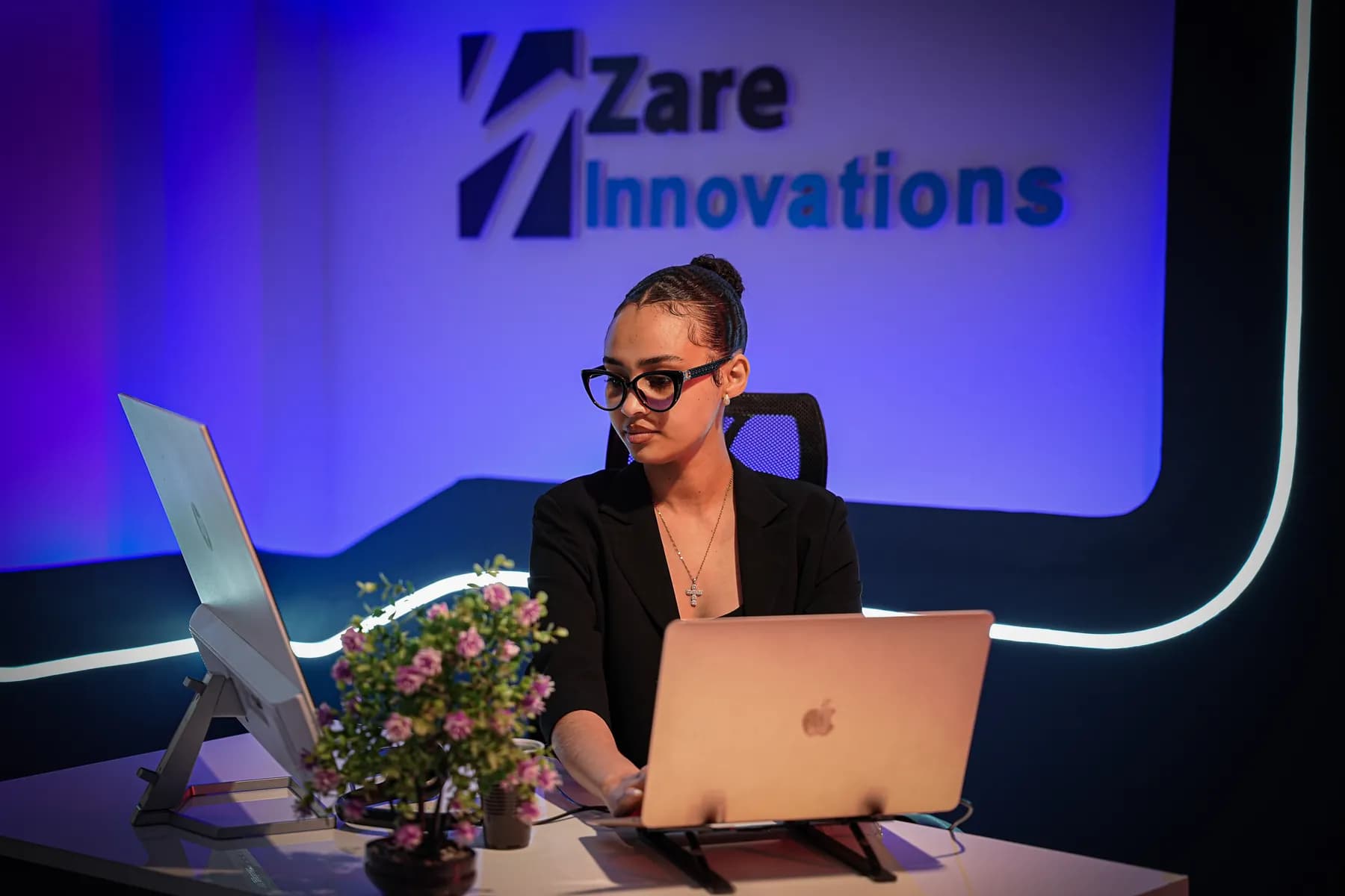 A Zare operations specialist working at her station beneath the company logo wall